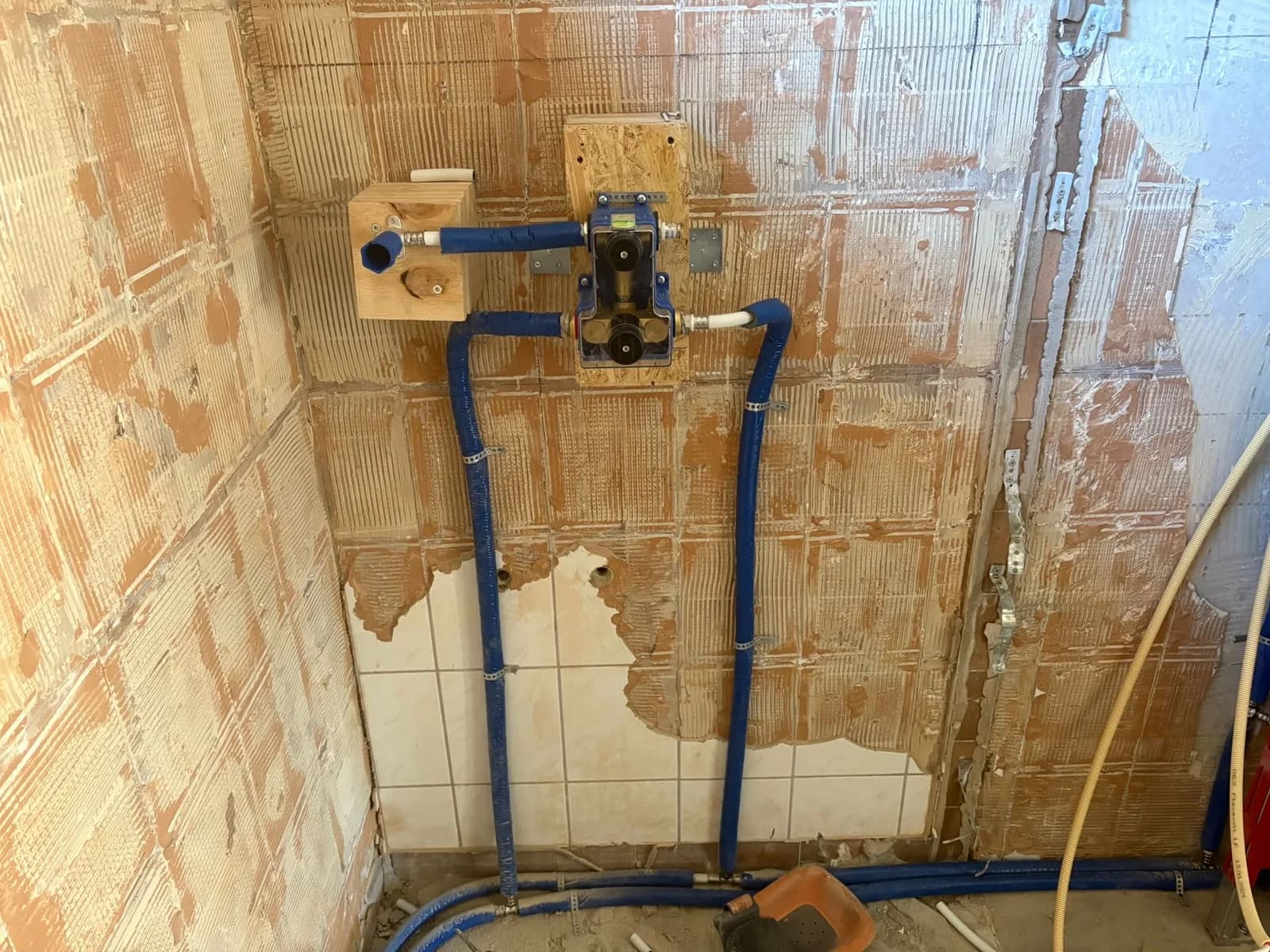 Ingebouwde thermostaatkraan met aangelegde waterleidingen in een badkamerwand