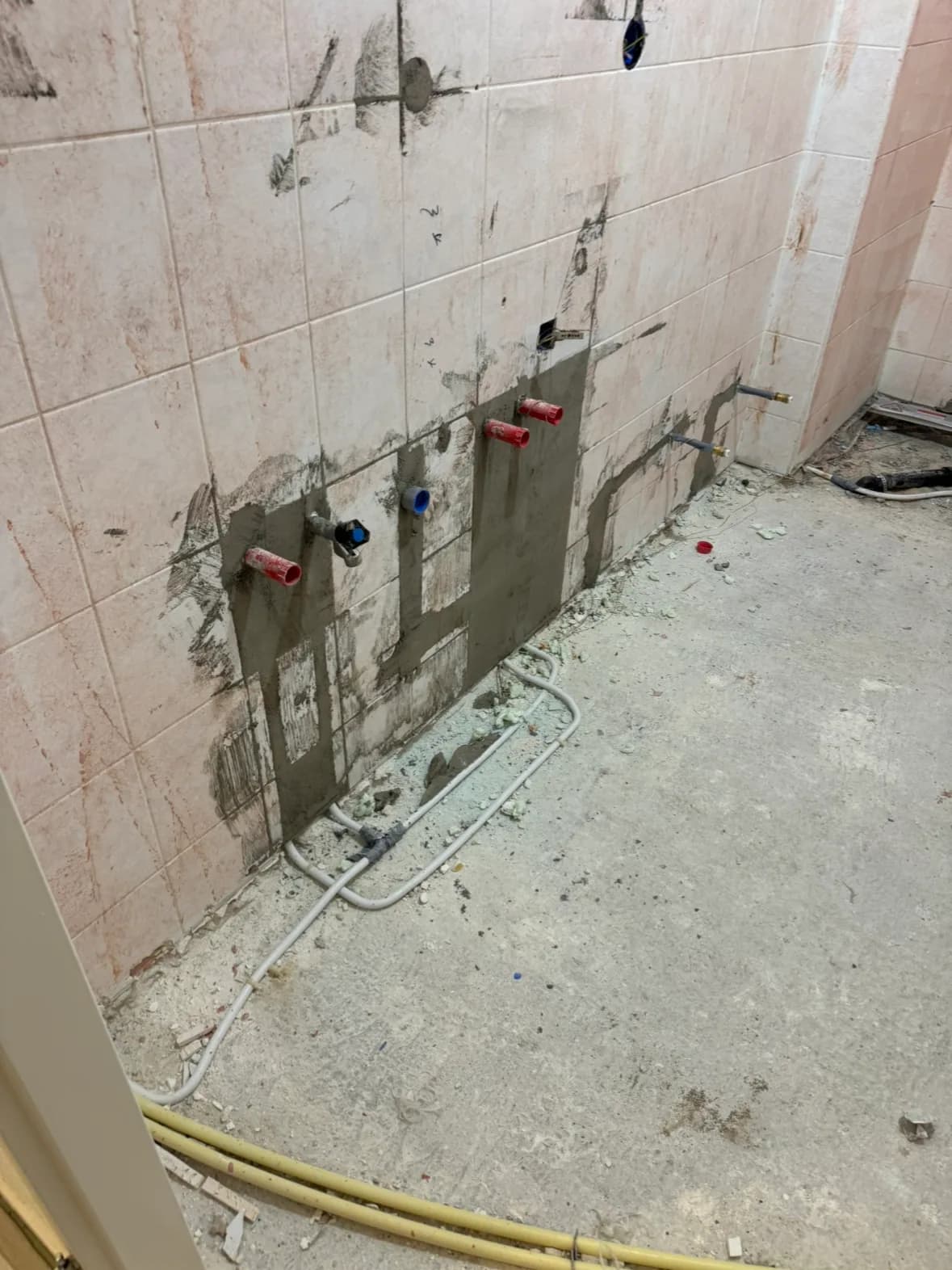 Opengelegde wand met water- en gasleidingen tijdens leidingwerk in een badkamer