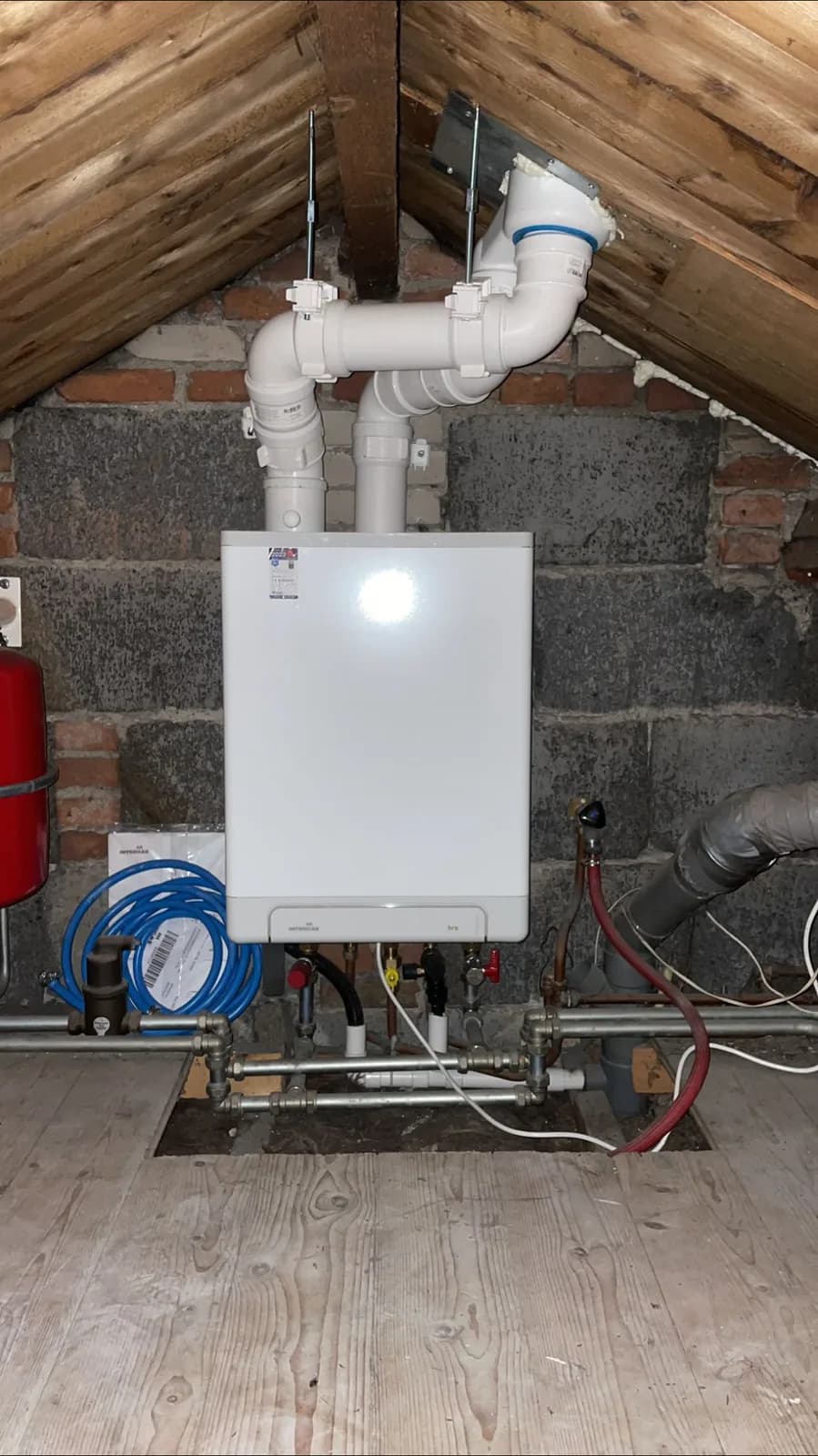 CV-ketel met expansievat, geplaatst op een zolder tussen de dakbalken
