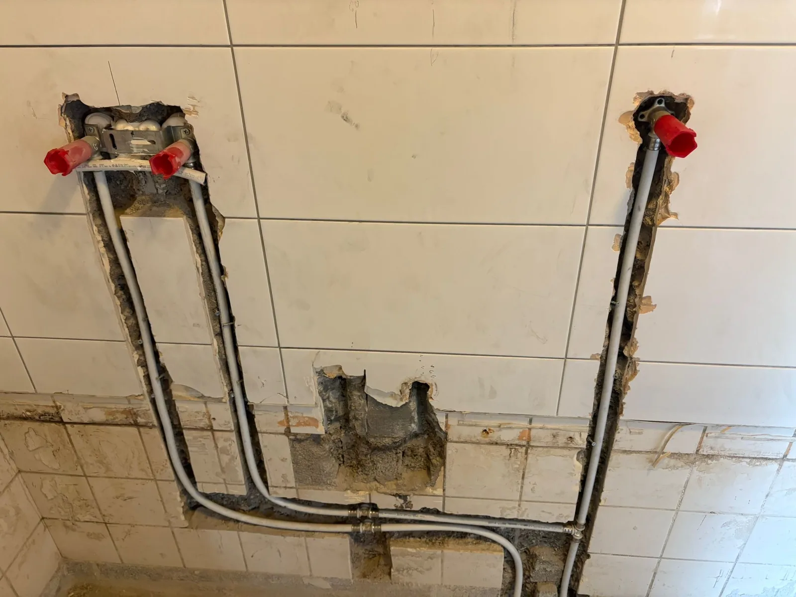 Gestripte tegelwand met afgedopte leidingen tijdens een renovatie