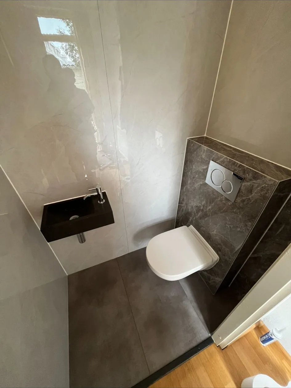 Toilet met natuursteenlook tegels, hangtoilet en zwart fonteintje