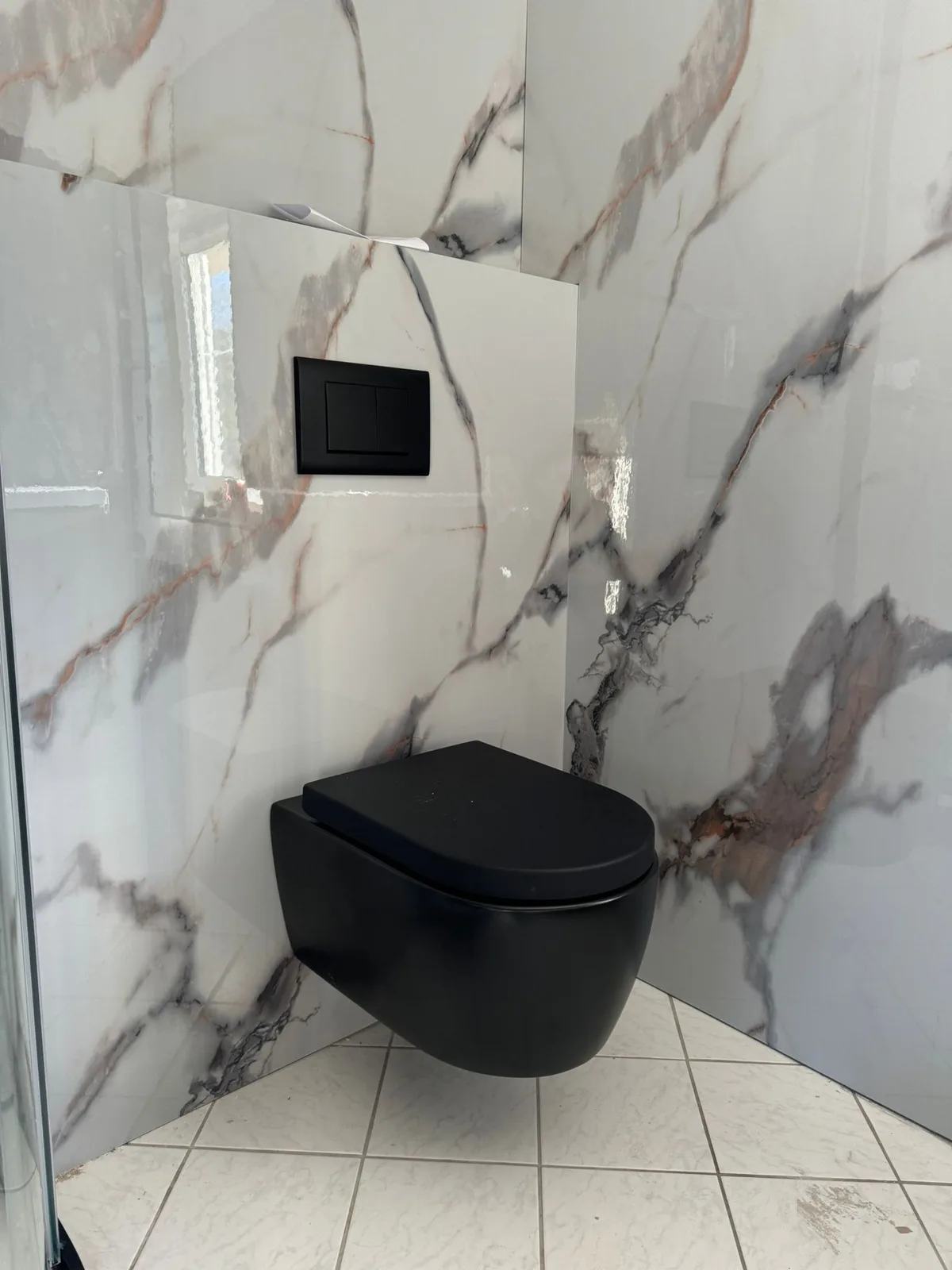 Afgewerkt toilet met zwart hangtoilet en marmerlook tegelwerk