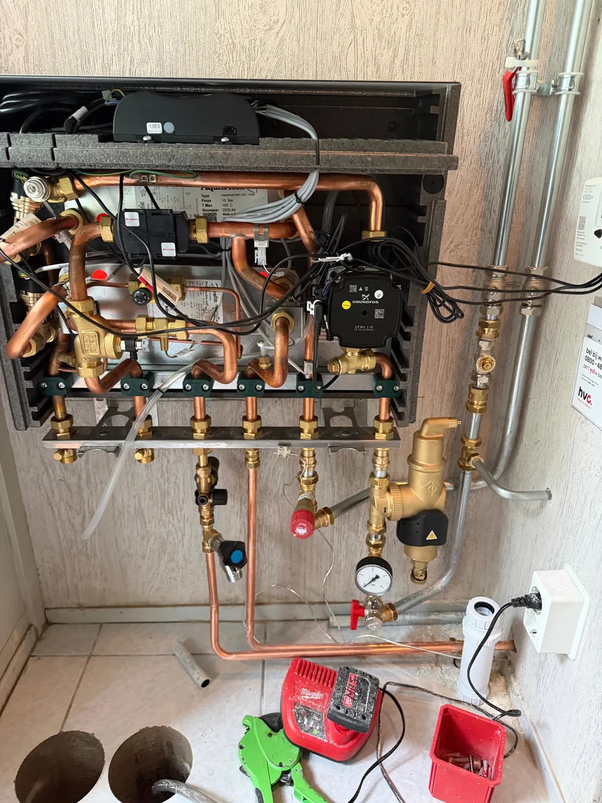 Geopende warmtepompmodule met koperen verdeler, circulatiepomp en manometer